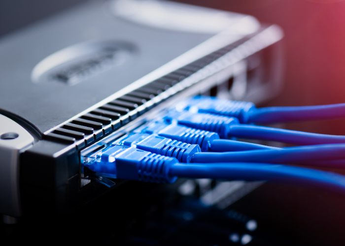 A router with four cables to show the importance of spectrum analyzers in wireless surveys. 