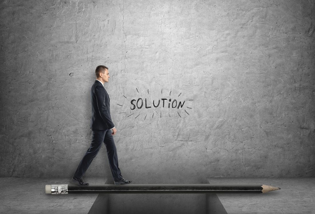 A man walking over a pencil, with the word solution written on the wall behind him showing an industry leader finding a solution to the digital skills gap.